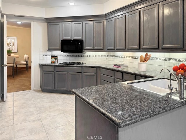 kitchen featuring light tile patterned flooring, dark brown cabinetry, sink, and dark stone countertops