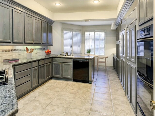 kitchen with black appliances, light stone counters, kitchen peninsula, and sink