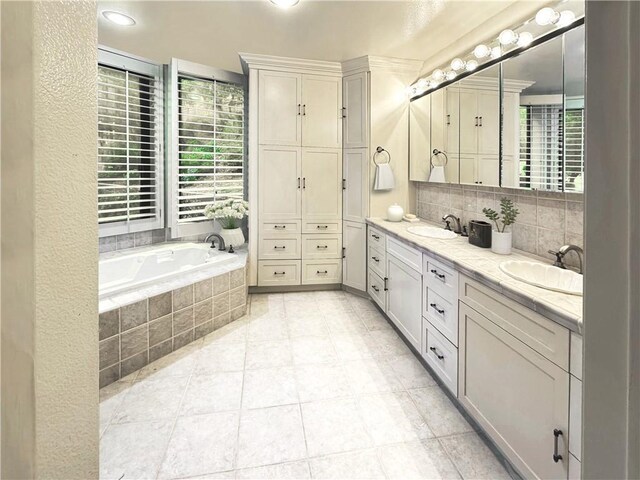 bathroom with tile patterned flooring, vanity, and tiled bath