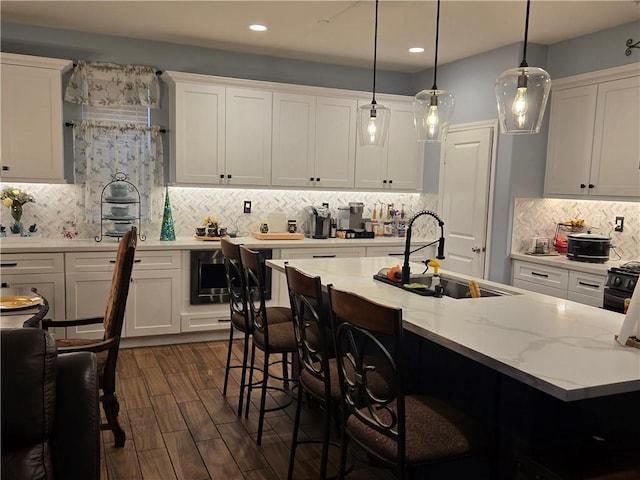 kitchen featuring pendant lighting, backsplash, white cabinetry, and sink