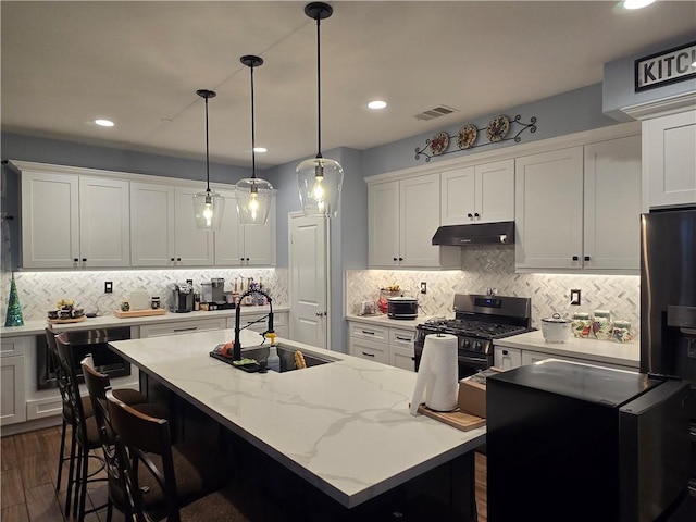 kitchen with a center island with sink, pendant lighting, sink, and appliances with stainless steel finishes