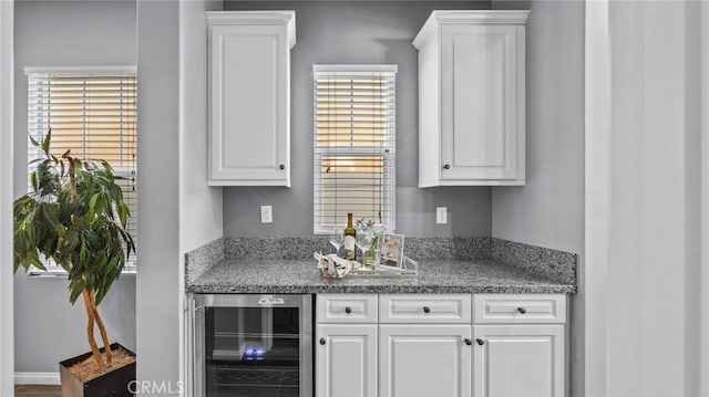 bar featuring wine cooler and white cabinetry