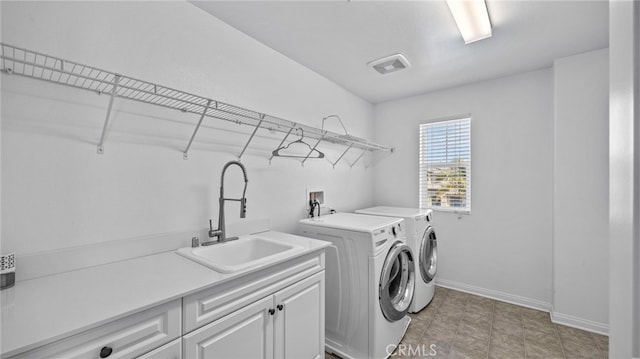 clothes washing area with cabinets, washer and clothes dryer, and sink