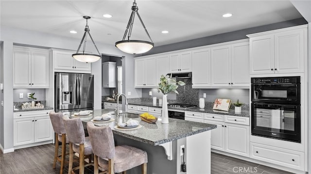 kitchen featuring white cabinetry, sink, stainless steel appliances, and an island with sink