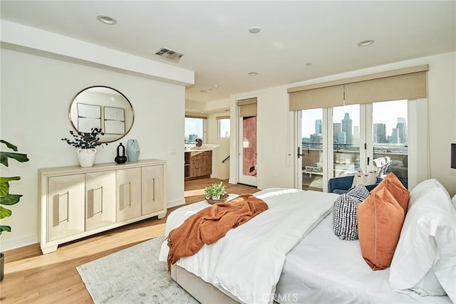 bedroom featuring access to outside, ensuite bath, and light hardwood / wood-style flooring