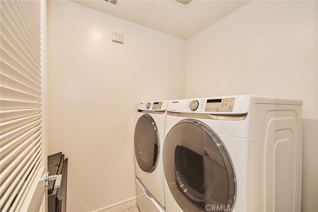 clothes washing area with separate washer and dryer and light tile patterned floors