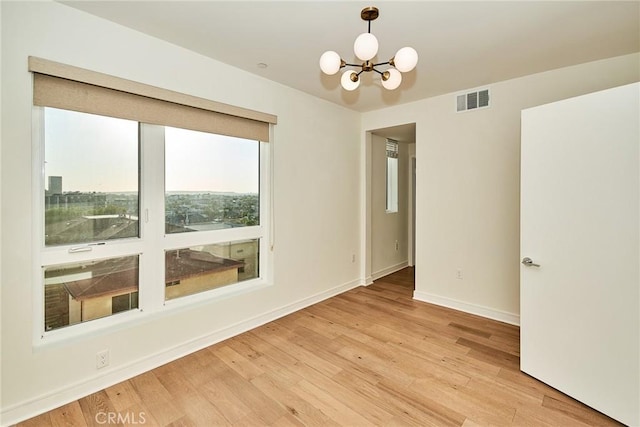 unfurnished room featuring hardwood / wood-style flooring and an inviting chandelier