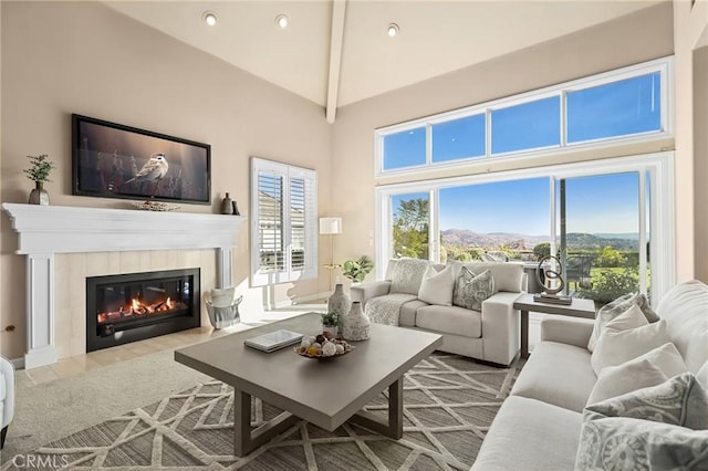 living room featuring high vaulted ceiling, a tile fireplace, and beamed ceiling