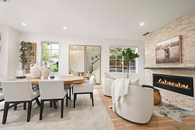 dining space featuring a healthy amount of sunlight, a fireplace, and light hardwood / wood-style floors