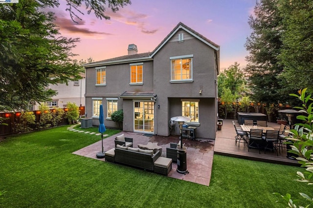 back house at dusk featuring central AC, a jacuzzi, outdoor lounge area, and a yard