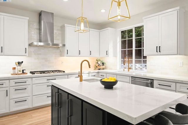 kitchen with appliances with stainless steel finishes, decorative light fixtures, wall chimney range hood, tasteful backsplash, and sink