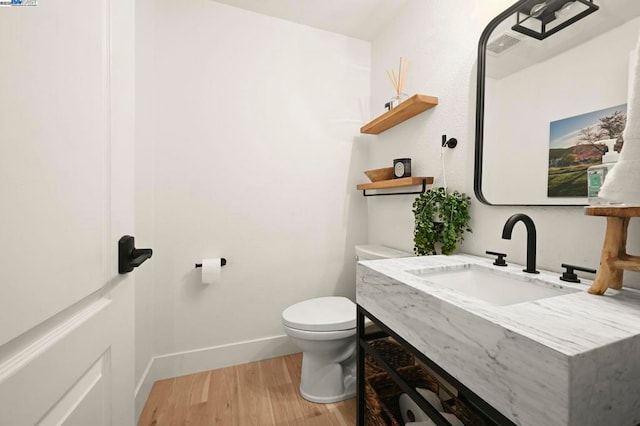 bathroom featuring toilet, wood-type flooring, and sink