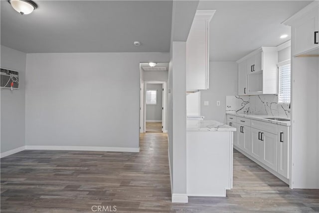 kitchen with white cabinetry, tasteful backsplash, light stone countertops, a healthy amount of sunlight, and dark hardwood / wood-style flooring