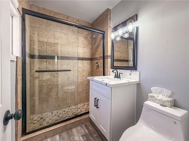 bathroom with walk in shower, hardwood / wood-style floors, vanity, and toilet