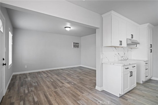 kitchen featuring decorative backsplash, light stone countertops, white cabinets, and light wood-type flooring