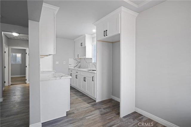 kitchen with sink, light stone counters, dark hardwood / wood-style flooring, decorative backsplash, and white cabinets