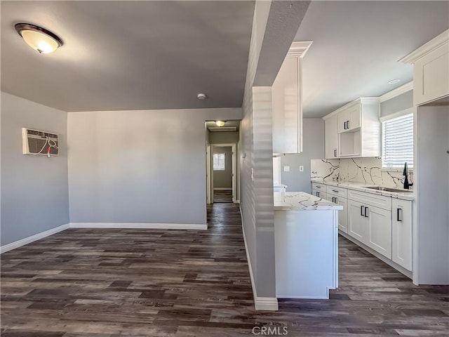 kitchen featuring sink, white cabinets, decorative backsplash, light stone counters, and dark wood-type flooring