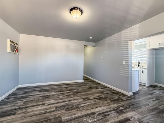 spare room featuring dark hardwood / wood-style flooring, a wall mounted AC, and sink