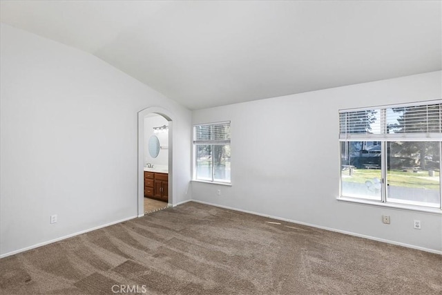 unfurnished bedroom featuring carpet flooring, connected bathroom, and lofted ceiling