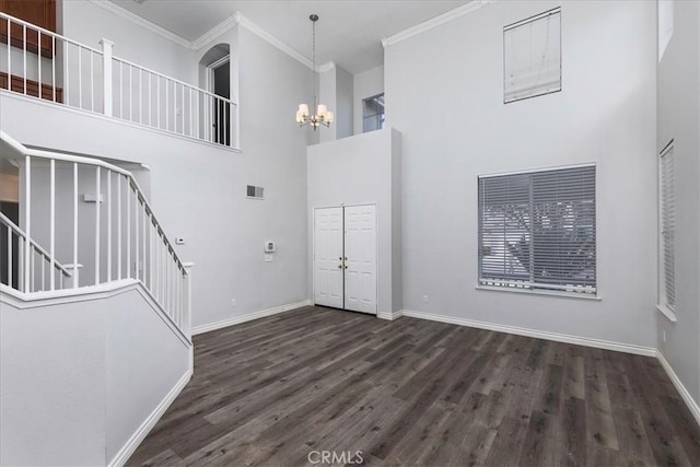 entrance foyer with a notable chandelier, ornamental molding, dark wood-type flooring, and a high ceiling