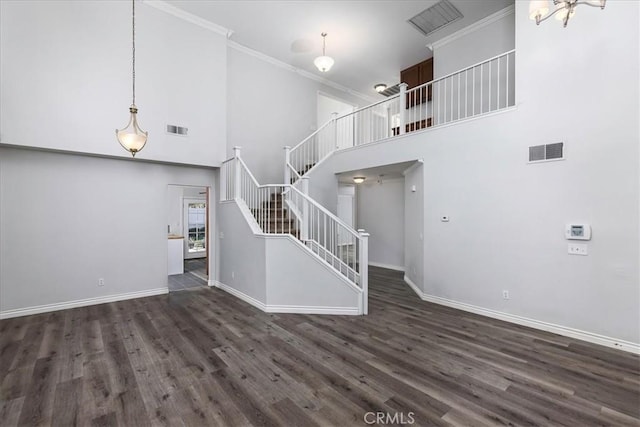 unfurnished living room featuring dark hardwood / wood-style flooring, a towering ceiling, and crown molding