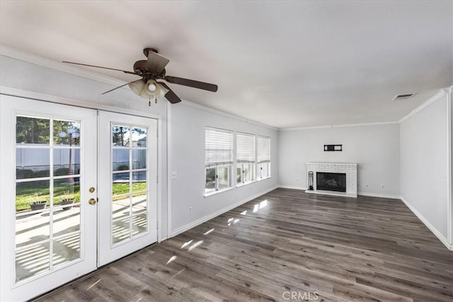 unfurnished living room with french doors, dark hardwood / wood-style floors, ceiling fan, ornamental molding, and a fireplace