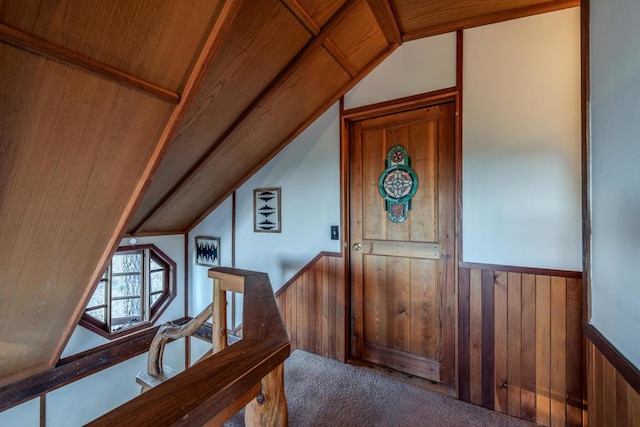 interior space featuring carpet, lofted ceiling, wooden ceiling, and wooden walls