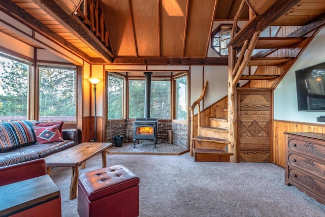 living room featuring a wood stove, wooden walls, carpet, and a wealth of natural light