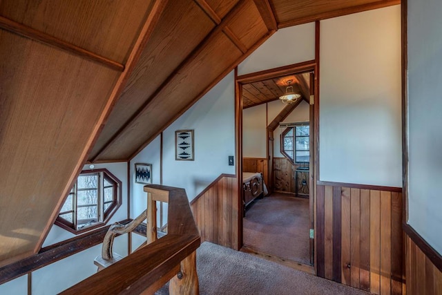 interior space featuring wood walls, carpet floors, wooden ceiling, and lofted ceiling