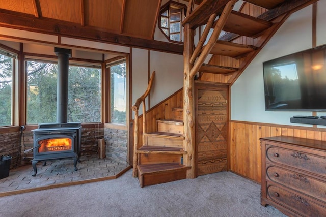 stairway with carpet, a wood stove, and wood walls