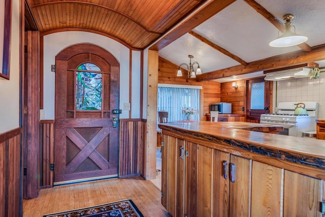 kitchen with light wood-type flooring, vaulted ceiling, extractor fan, an inviting chandelier, and white range with gas stovetop