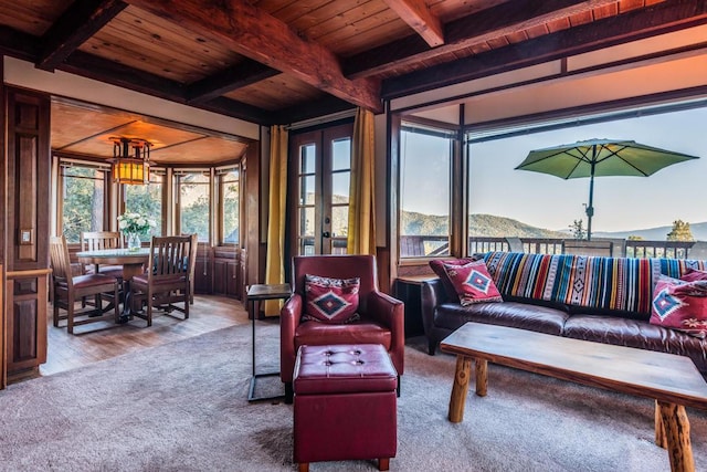 sunroom with a mountain view, french doors, beamed ceiling, and wooden ceiling