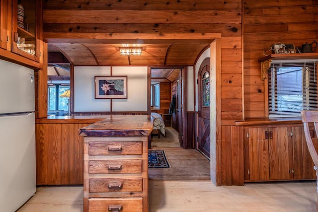 kitchen with wood ceiling, wooden walls, and fridge