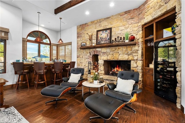 living area with a stone fireplace, dark wood-type flooring, and indoor bar