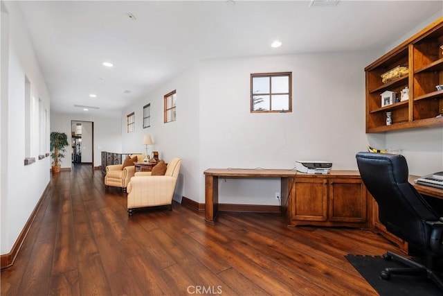 home office with built in desk and dark hardwood / wood-style flooring