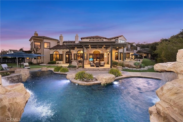 pool at dusk featuring a pergola and a patio