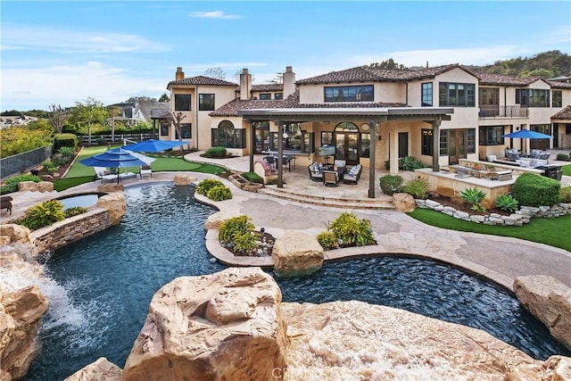 rear view of house featuring pool water feature, a small pond, a fenced in pool, and a patio area