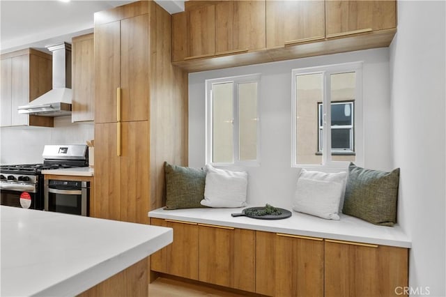 kitchen with appliances with stainless steel finishes, backsplash, and wall chimney range hood