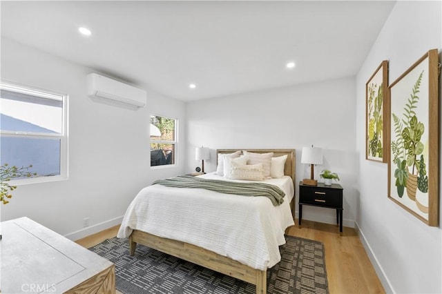 bedroom with light hardwood / wood-style flooring and a wall mounted AC