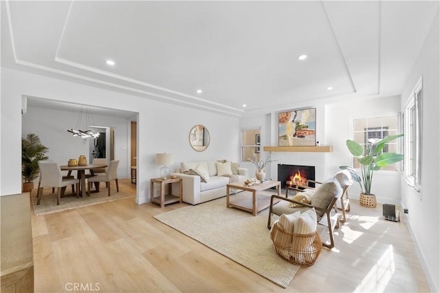 living room with a tray ceiling and light wood-type flooring