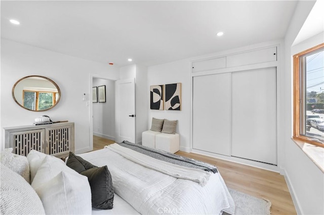 bedroom featuring multiple windows, a closet, and light hardwood / wood-style floors