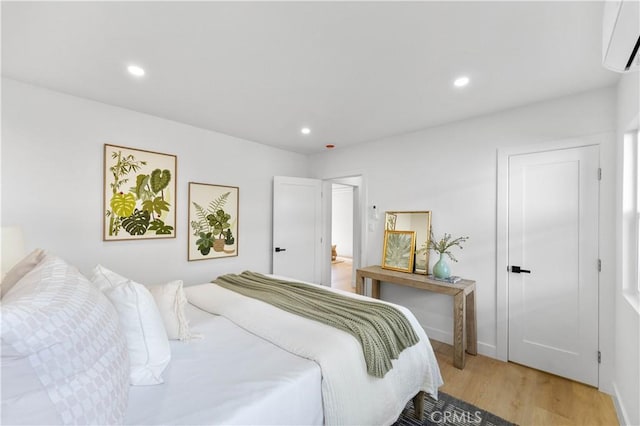 bedroom with a wall unit AC and wood-type flooring