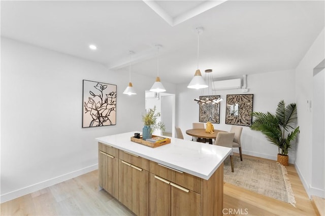 kitchen with a center island, decorative light fixtures, light hardwood / wood-style flooring, and an AC wall unit