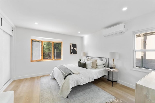 bedroom with light hardwood / wood-style flooring, an AC wall unit, and multiple windows