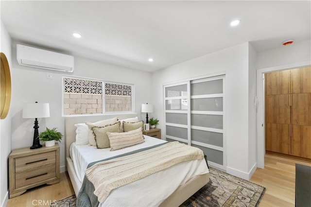 bedroom featuring light hardwood / wood-style floors, an AC wall unit, and a closet