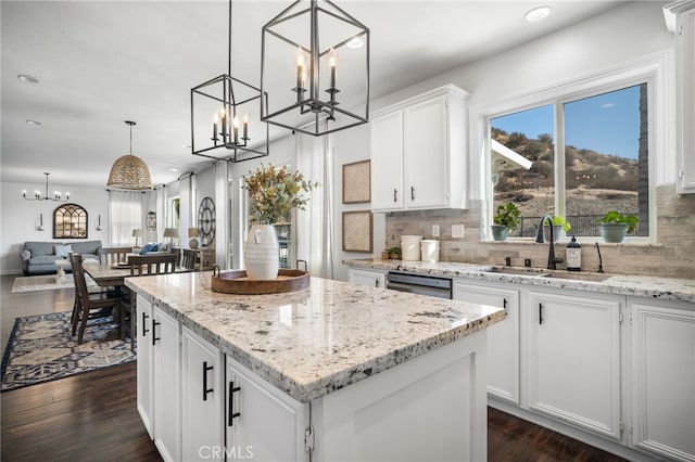 kitchen with sink, white cabinetry, decorative light fixtures, a center island, and decorative backsplash