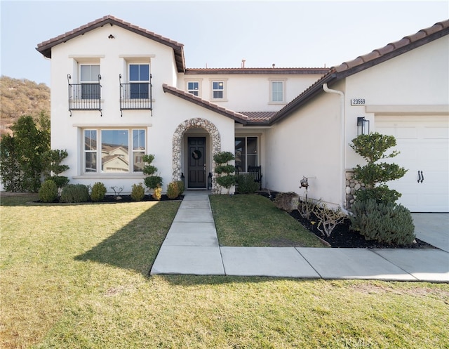 mediterranean / spanish house featuring a garage, a front lawn, and a balcony