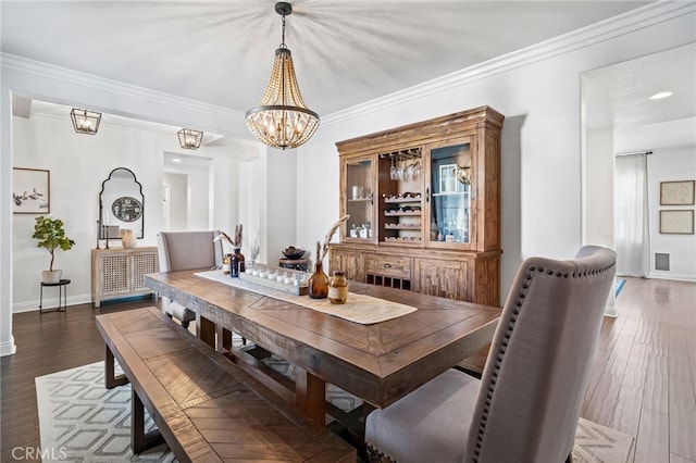 dining space with dark hardwood / wood-style flooring, ornamental molding, and a chandelier