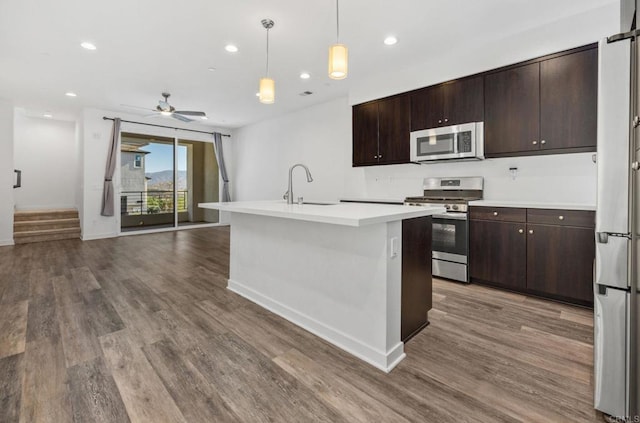 kitchen featuring appliances with stainless steel finishes, a kitchen island with sink, dark brown cabinets, and sink