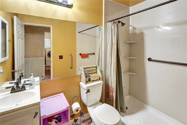 bathroom featuring walk in shower, vanity, washer / dryer, and toilet